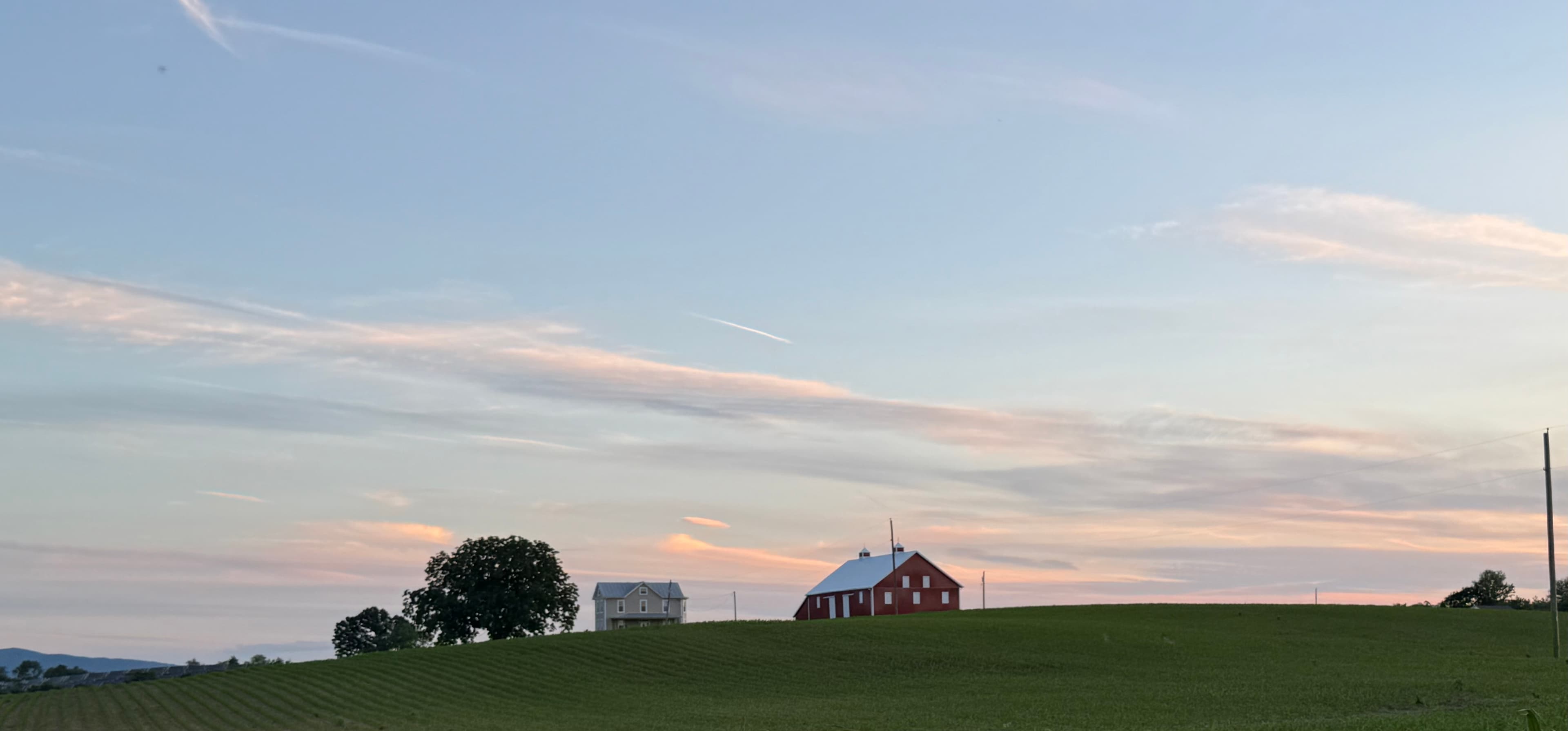 A red barn and farmhouse on a green Shenandoah Valley hilltop at dusk